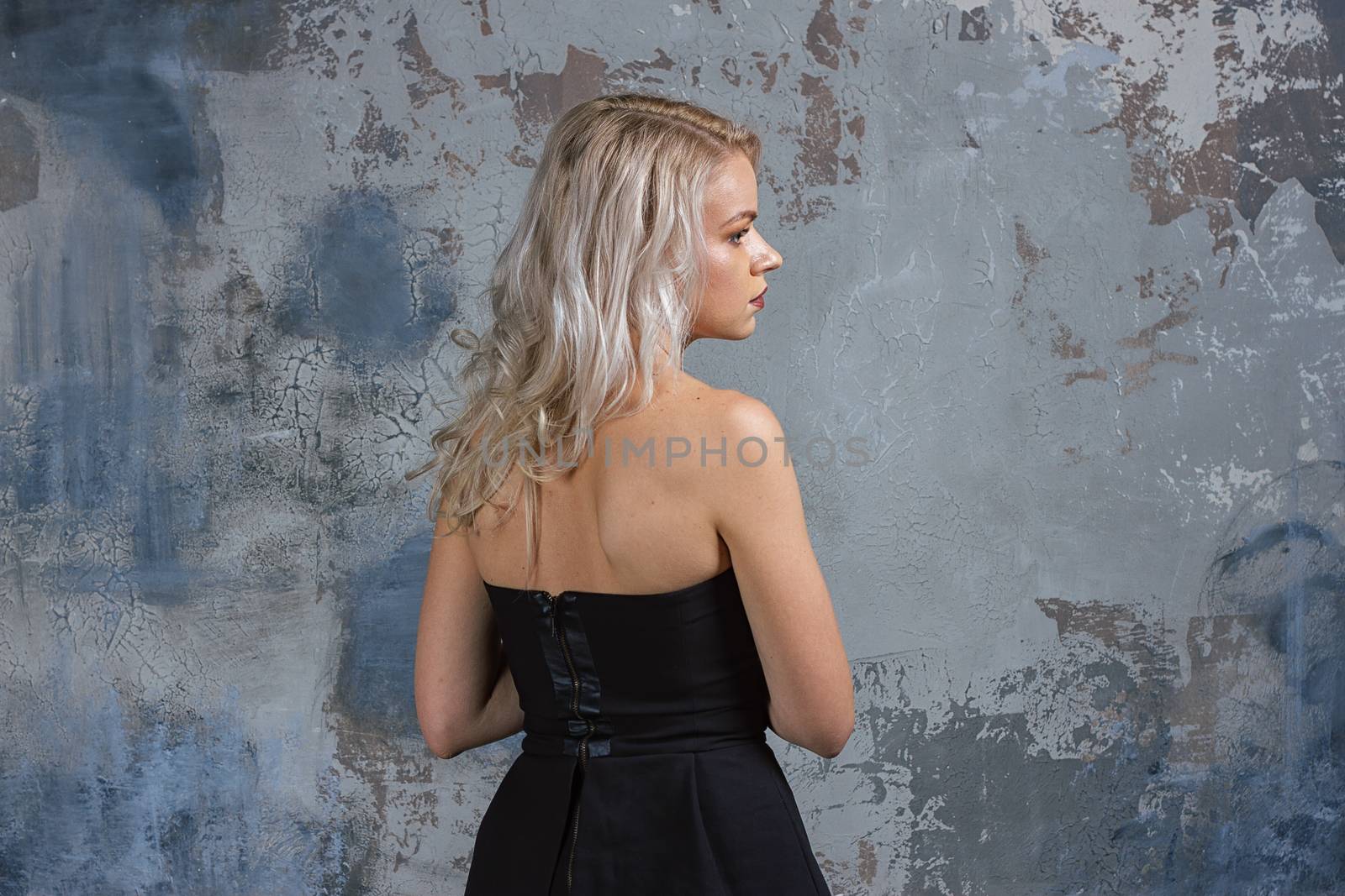 Portrait of a girl with long hair in youth clothes, Young beautiful girl near the wall her back