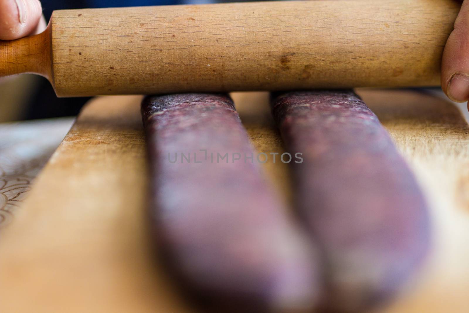 Closeup of man hands rolling over homemade sausages to make them flat for drying