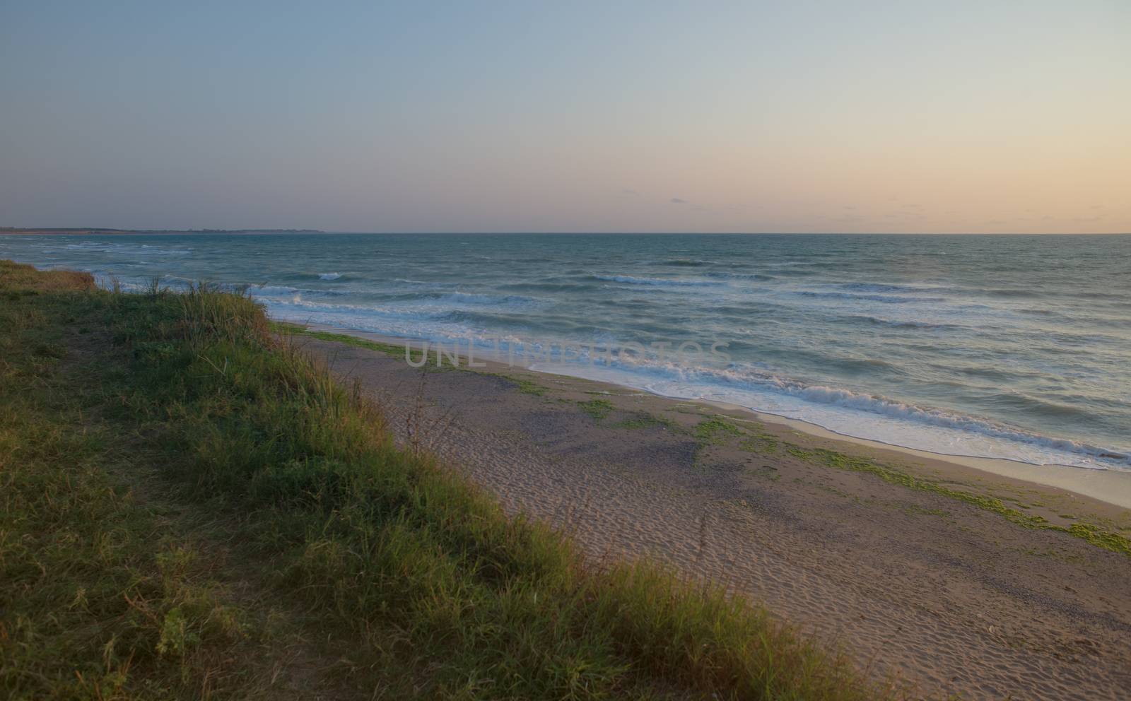 Beautiful empty beach on the sea or ocean shore on sunrise.