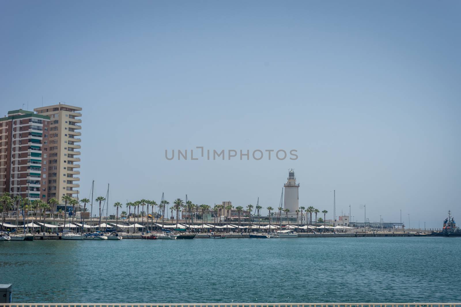 View of the lighthouse against the sea with palm trees at Malaga by ramana16