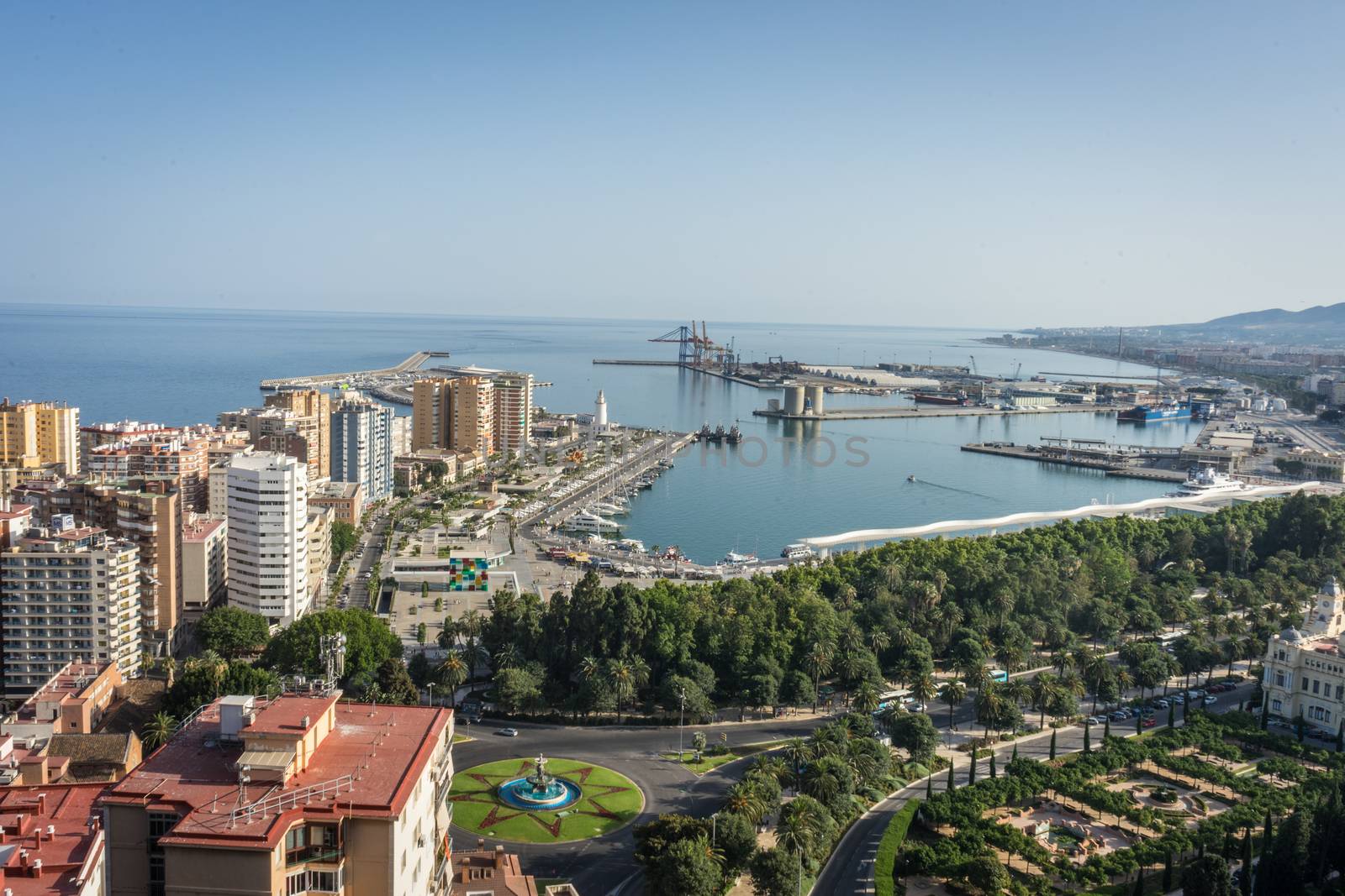 City skyline and harbour, sea port of Malaga overlooking the sea ocean in Malaga, Spain, Europe on a bright summer day with blue skies with trees