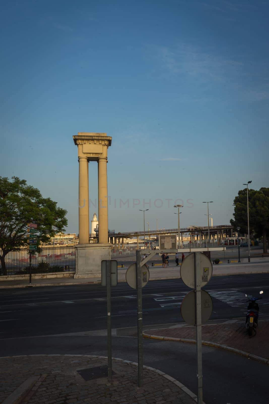 White lighthouse viewed through a pillar in Malaga, Spain, Europe at sunset