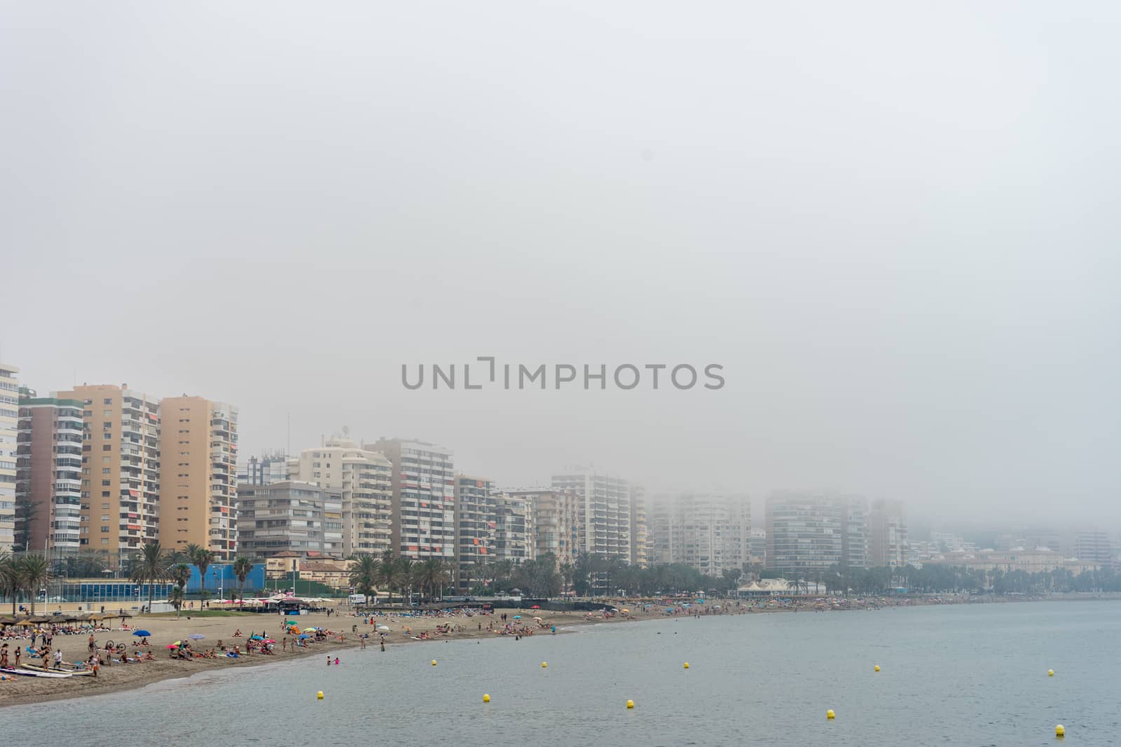 The building along the coastline at Malagueta beach covered by fog in Malaga, Spain, Europe on a foggy morning