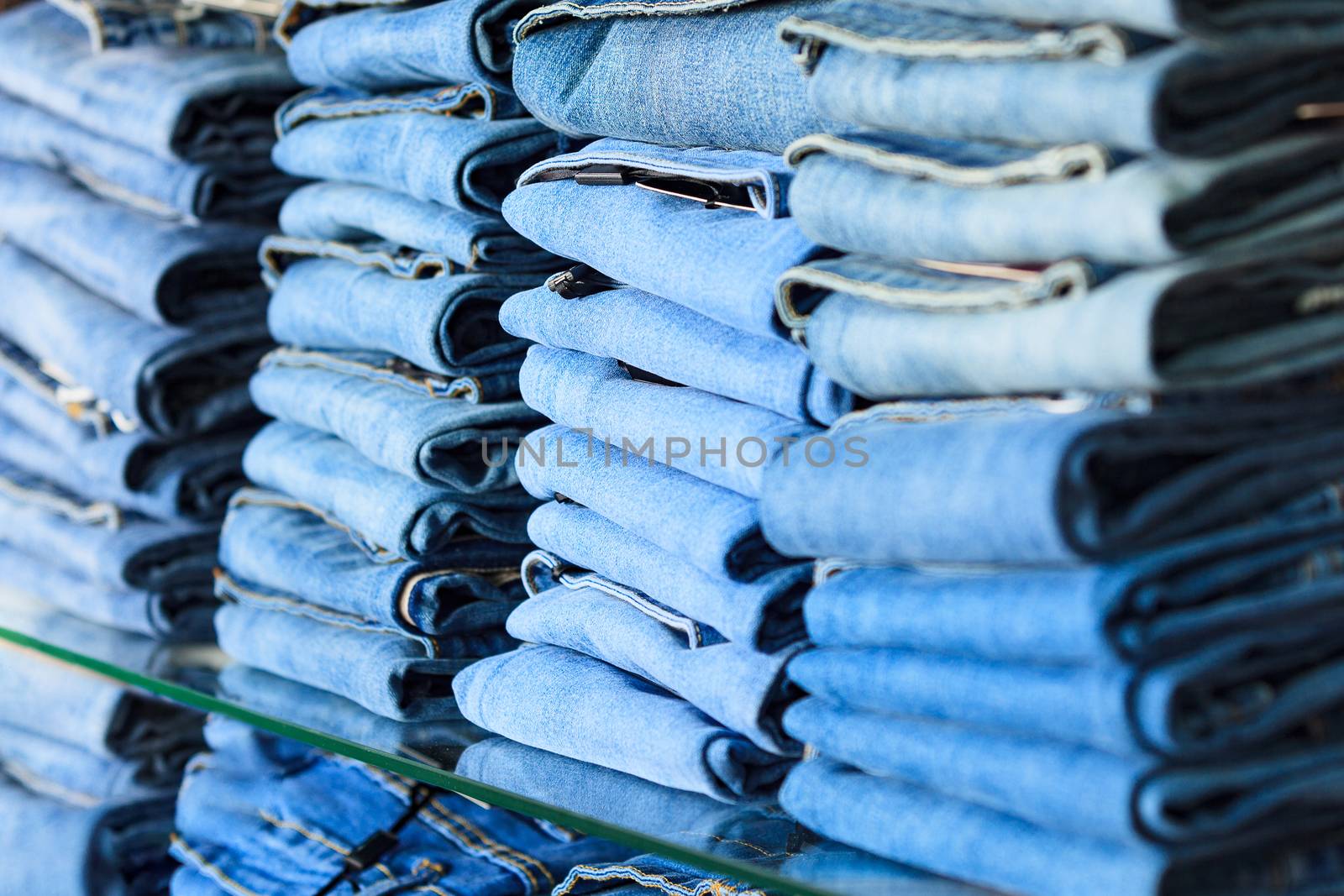 Closeup shot of stack of folded jeans in the fashion store by Nobilior