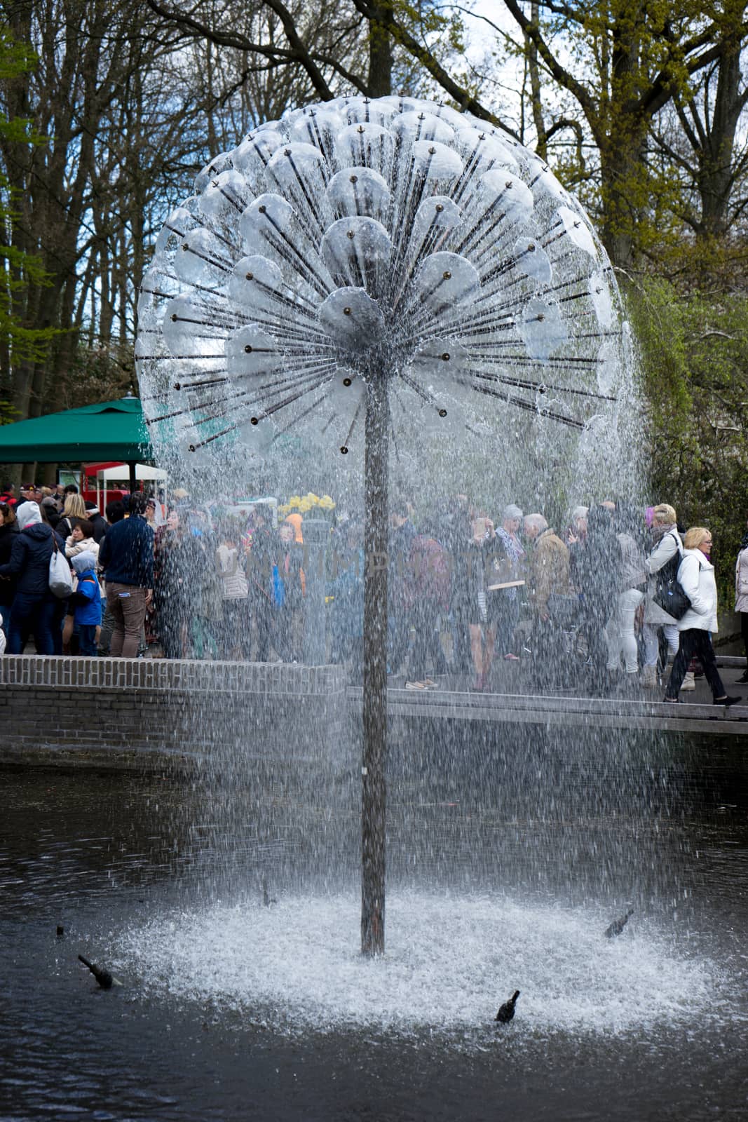 Lisse, Netherlands - April 17 : The Keukenhoff Tulip Gardens on April 17, 2016. Tourists gather near the water fountain  on a summer day