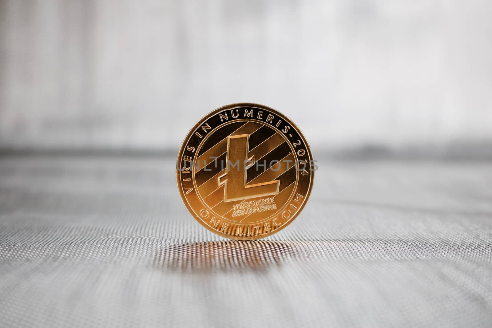 Cryptocurrency physical gold Litecoin coin on the silver background. Money concept.