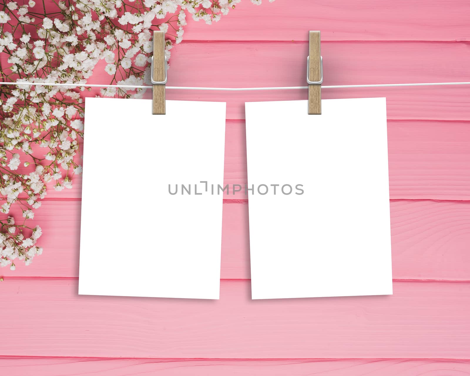Paper cards hanging on a clothesline with clothespins on wood pink background