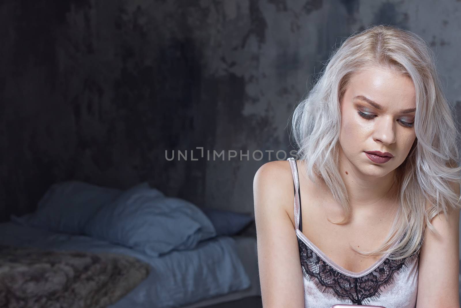 Blonde girl is sad near the bed