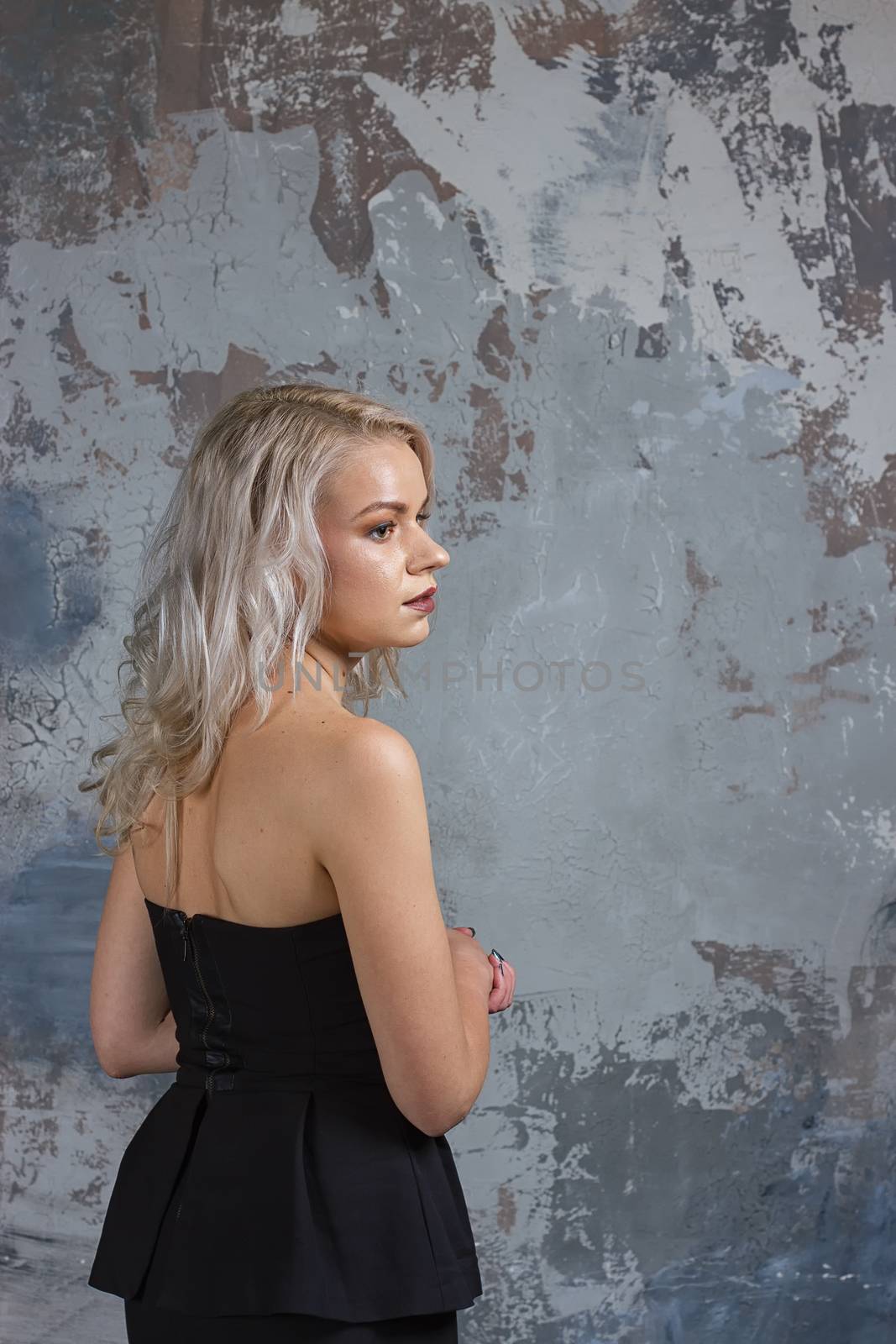 Portrait of a girl with long hair in youth clothes, Young beautiful girl near the wall her back