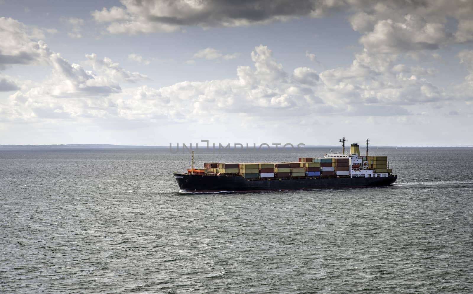 container ship on the sea with the bridge to denmark on the background