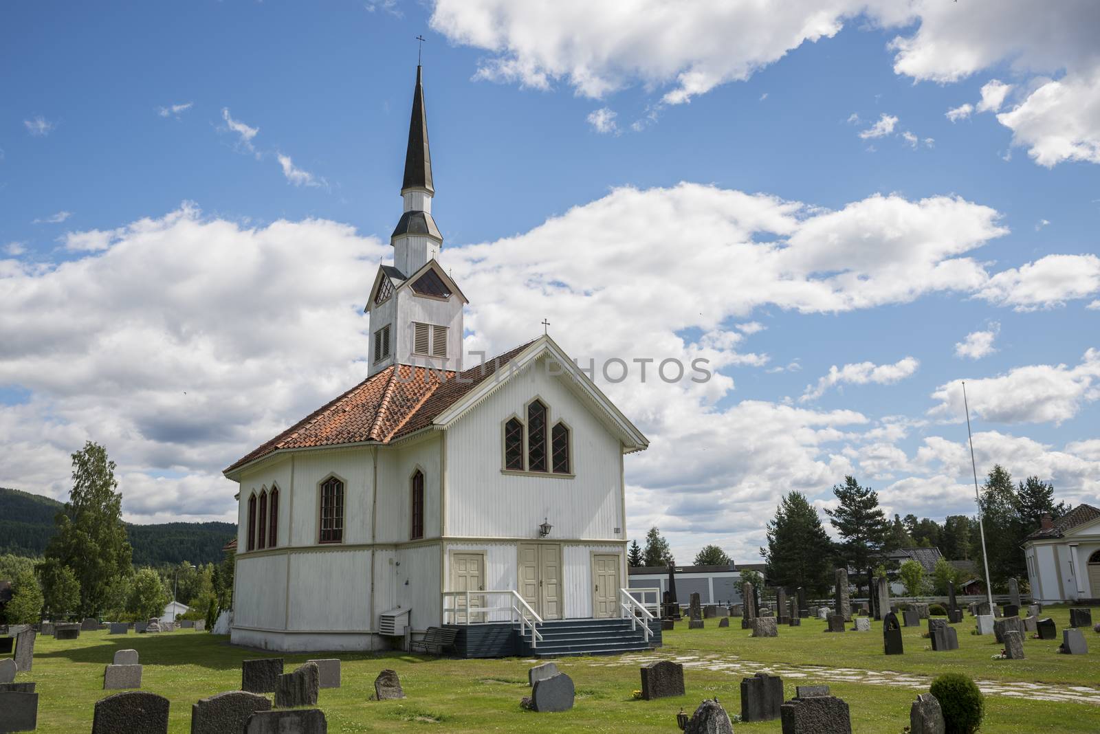 white wooden stave church near Leira in Norway with cemetery