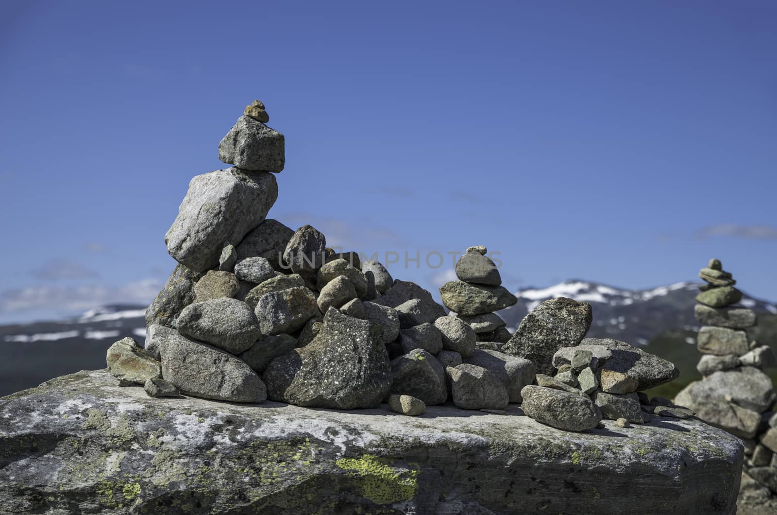 balanced stack of stones at Eidfjorden, Norway with snow and mountains as background