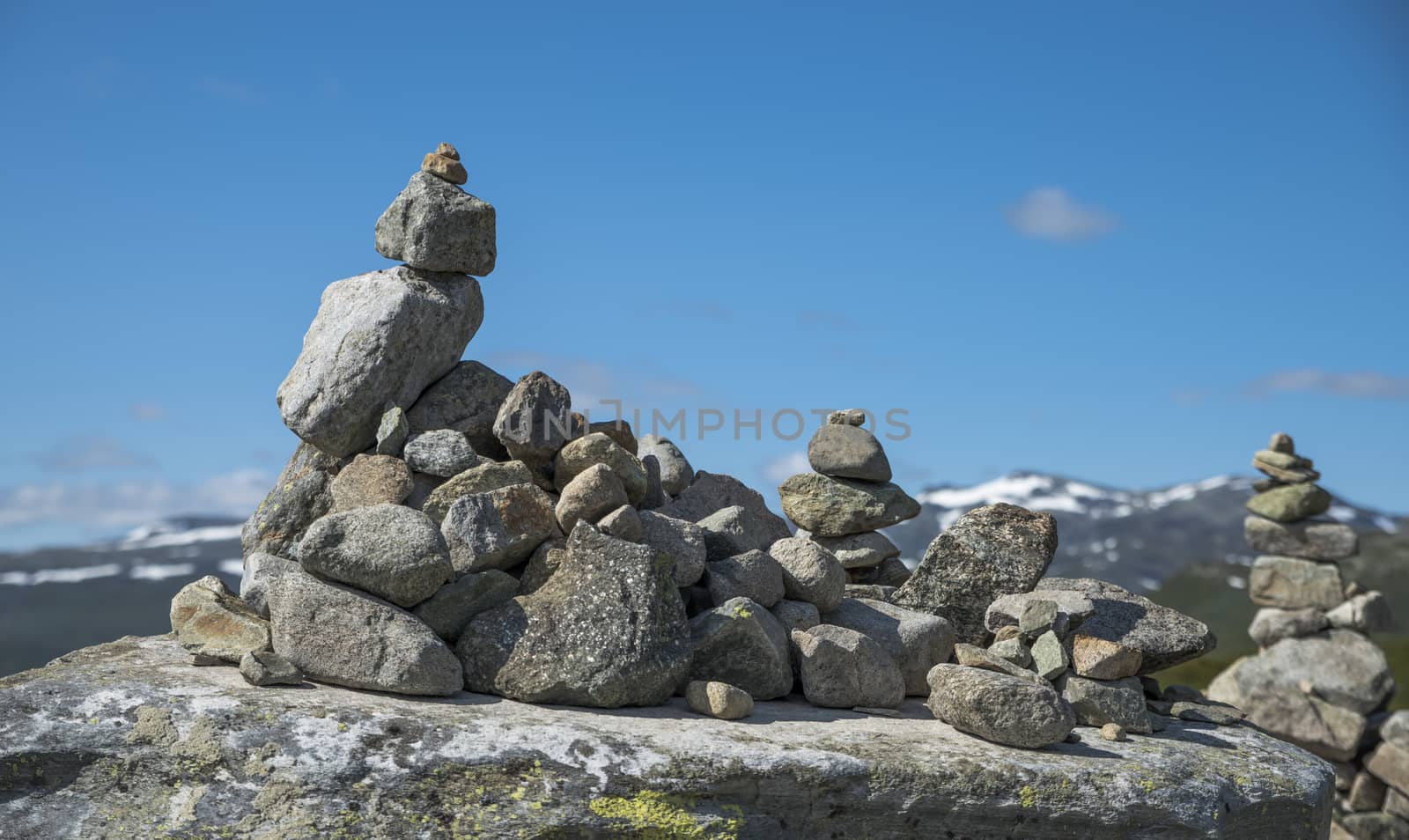 balanced stack of stones at Eidfjorden, Norway with snow and mountains as background