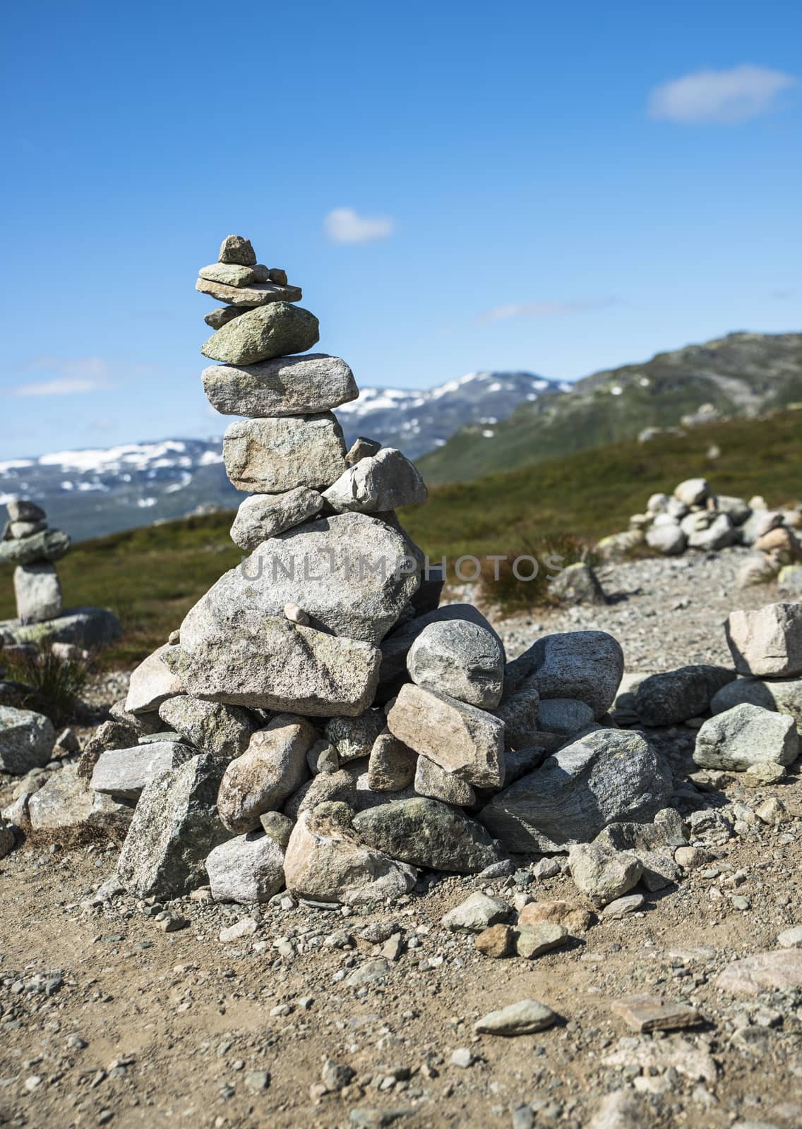 balanced stack of stones at Eidfjorden, Norway with snow and mountains as background