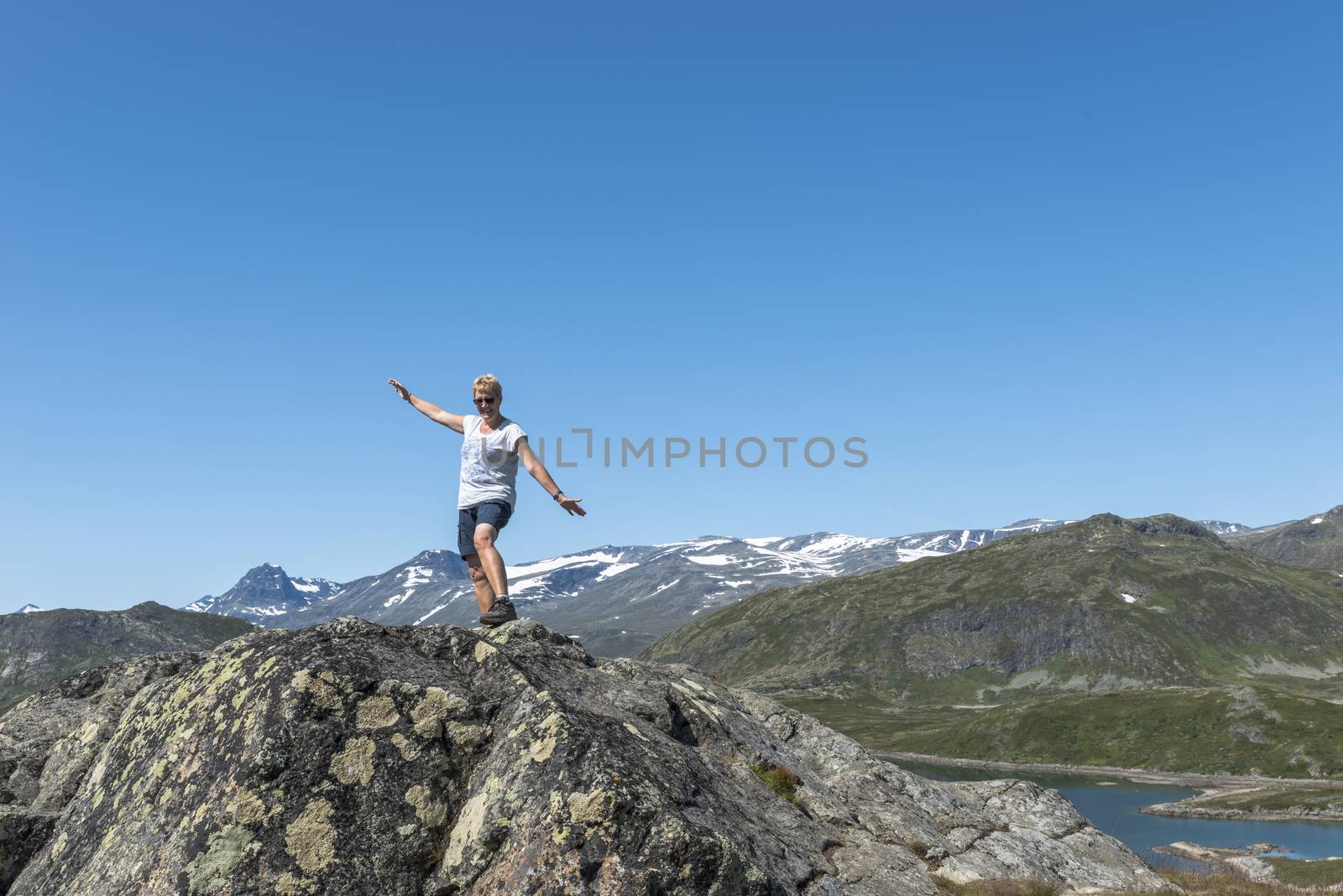 adult woman happy on a rock looking over the blue water by compuinfoto