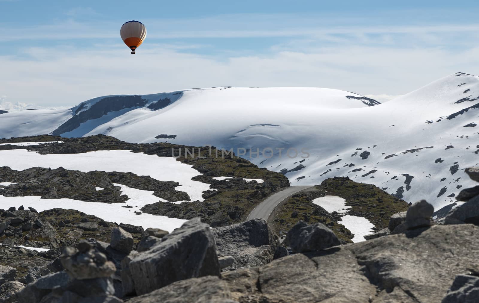 hot air balloon above the dalsnibba or road 63 touristic road to the high view of the geirangerfjord in norway with snow in summer on the tops of the mountains