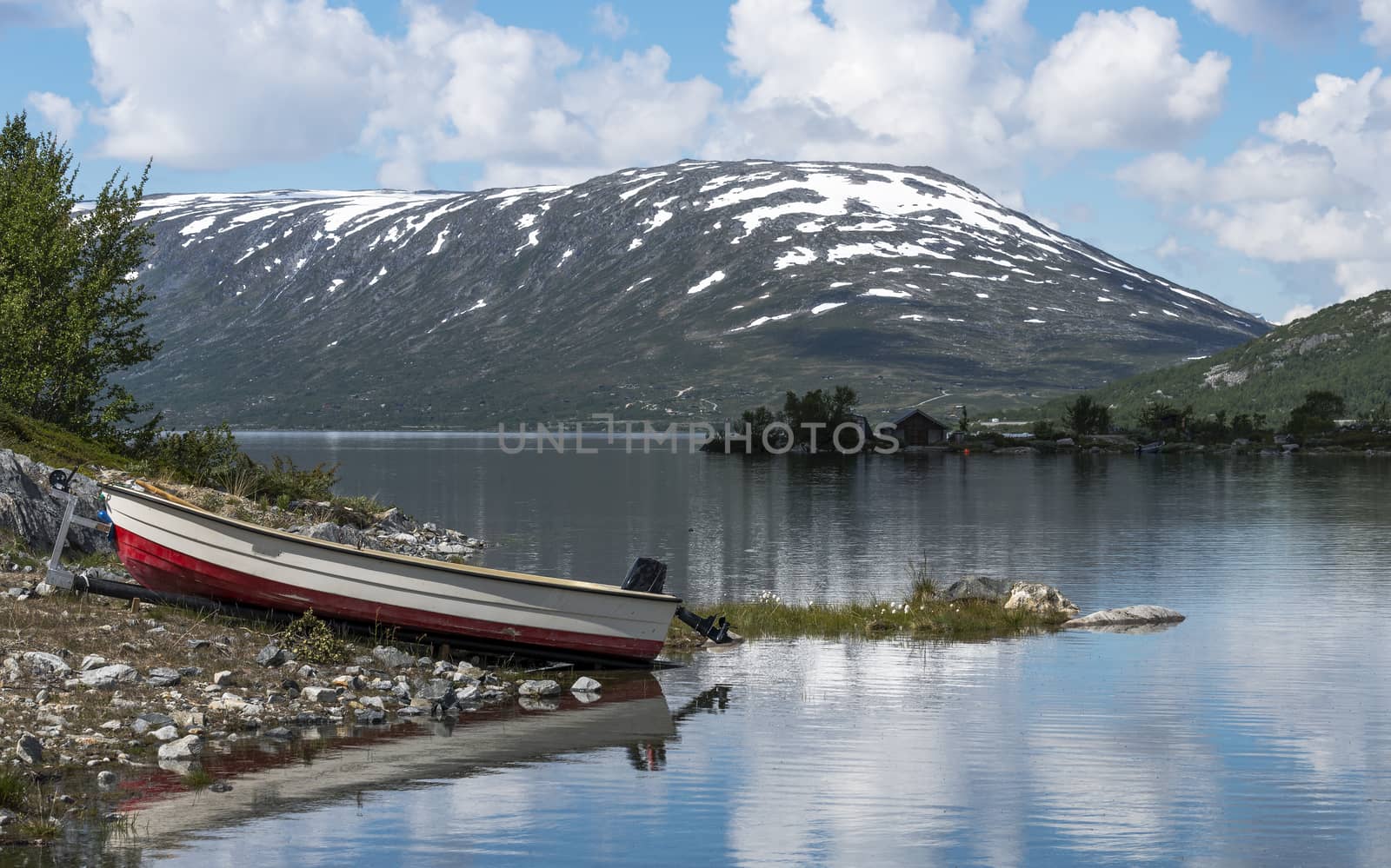 fjord in norway in the summer  with boat on  trailer and mountains with snow as background 