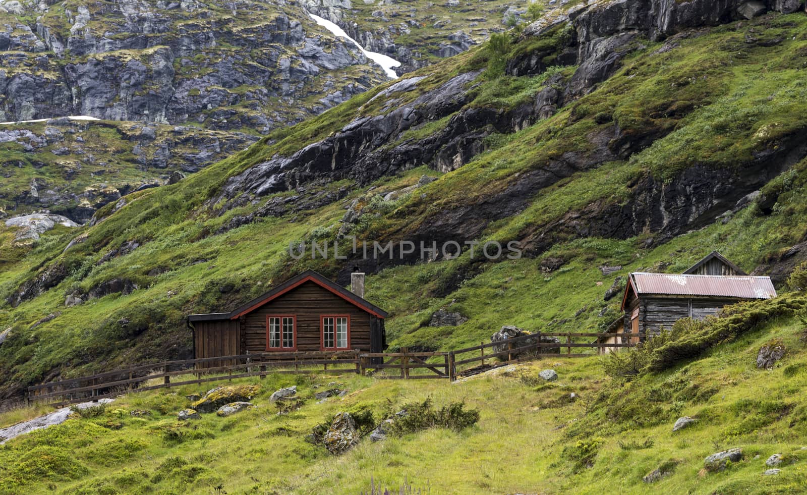 wooden house on the hills of the Jostedalsbreen nature park  in summer with snow on the mountains