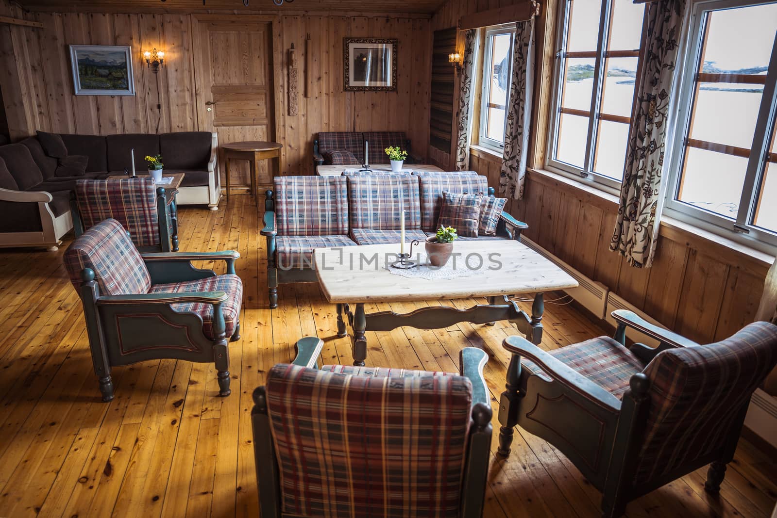 typical norway interior with outisde the snow on the mountains ans inside warm brown chairs and wooden table and floor