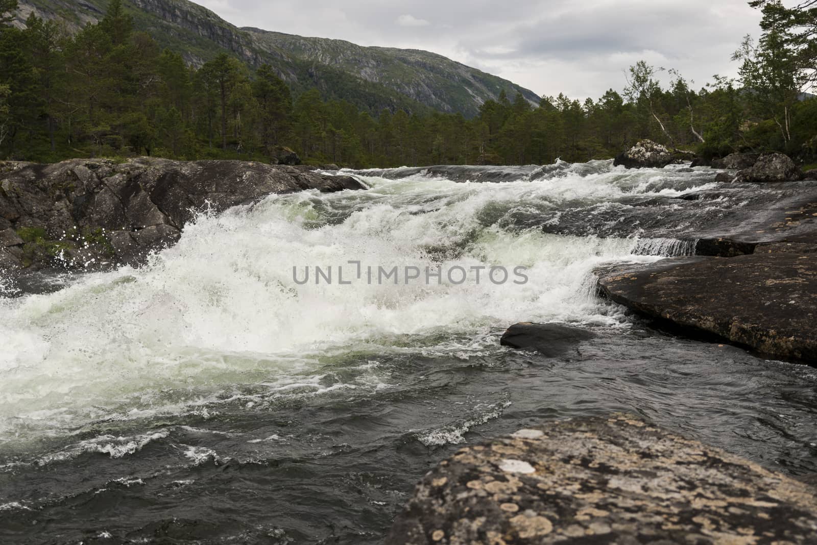 likholefossen waterfall in norway with mountains as background