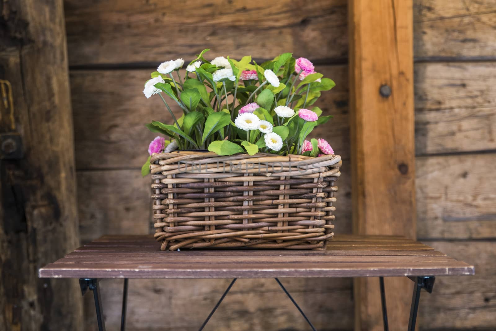 wicker basket with flowers in pink and white on old wooden table