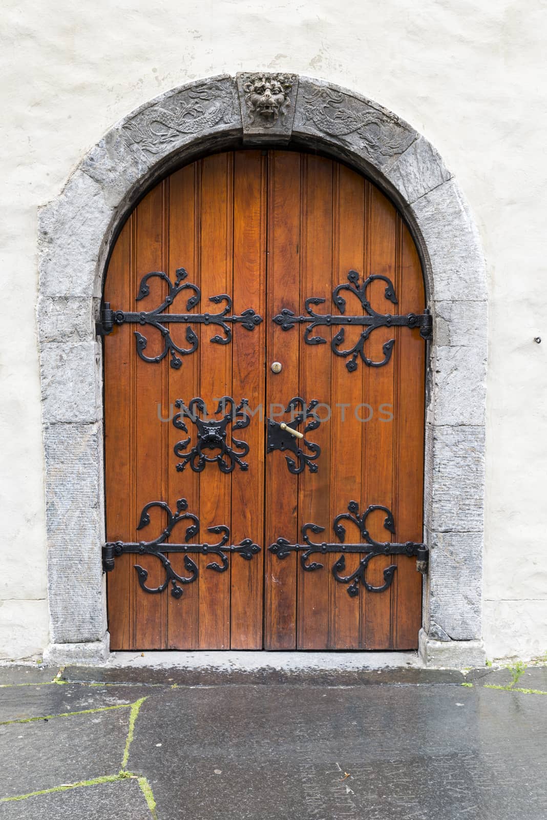 old vertical wooden door with black metal mfittings in ols white stone wall