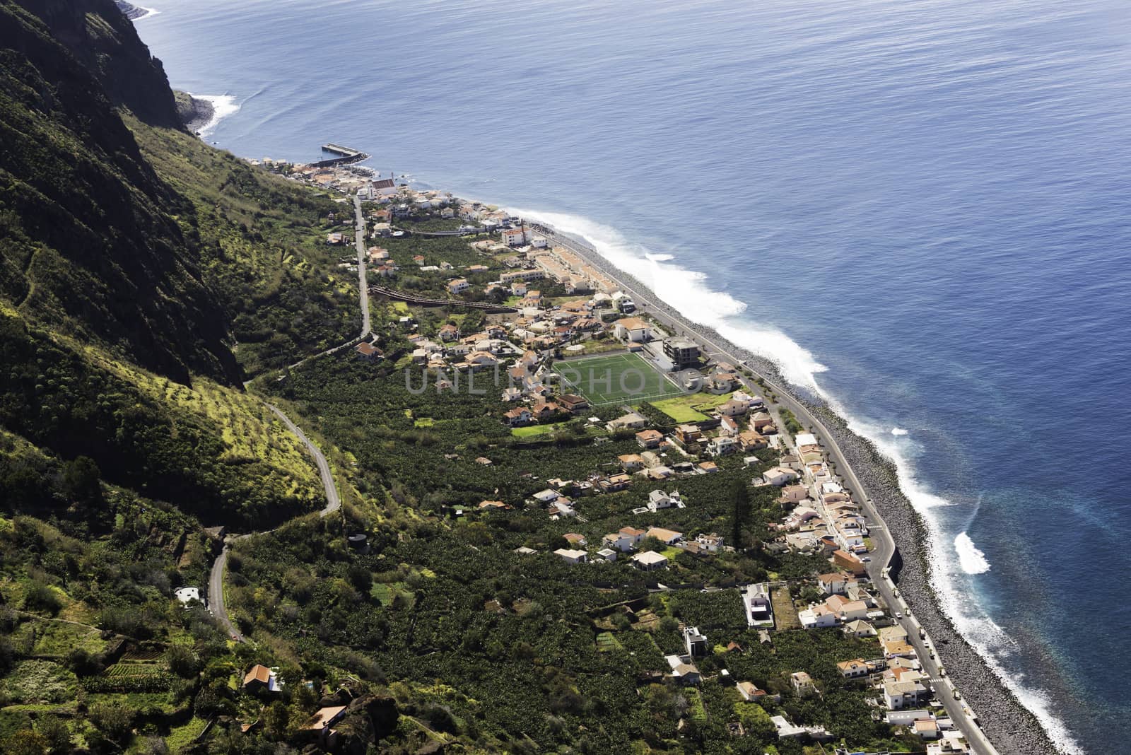 high mountains and the small road with hairpin above the small village Paul de mar with tennis court and coastline