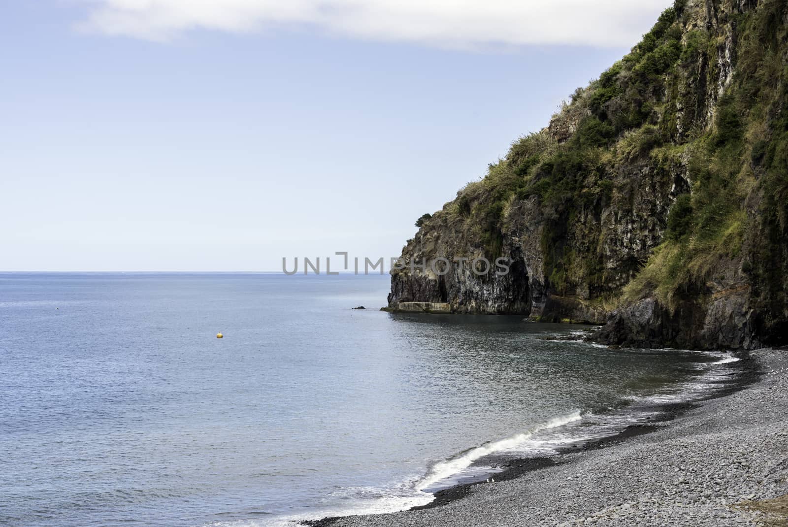 madeira coastline with ocean and rocks with calm sea and rocky beack