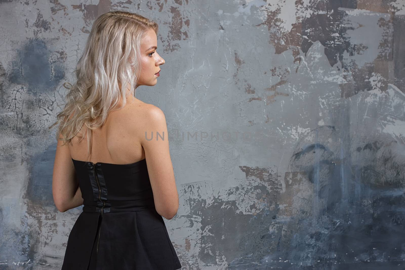 Portrait of a girl with long hair in youth clothes, Young beautiful girl near the wall her back