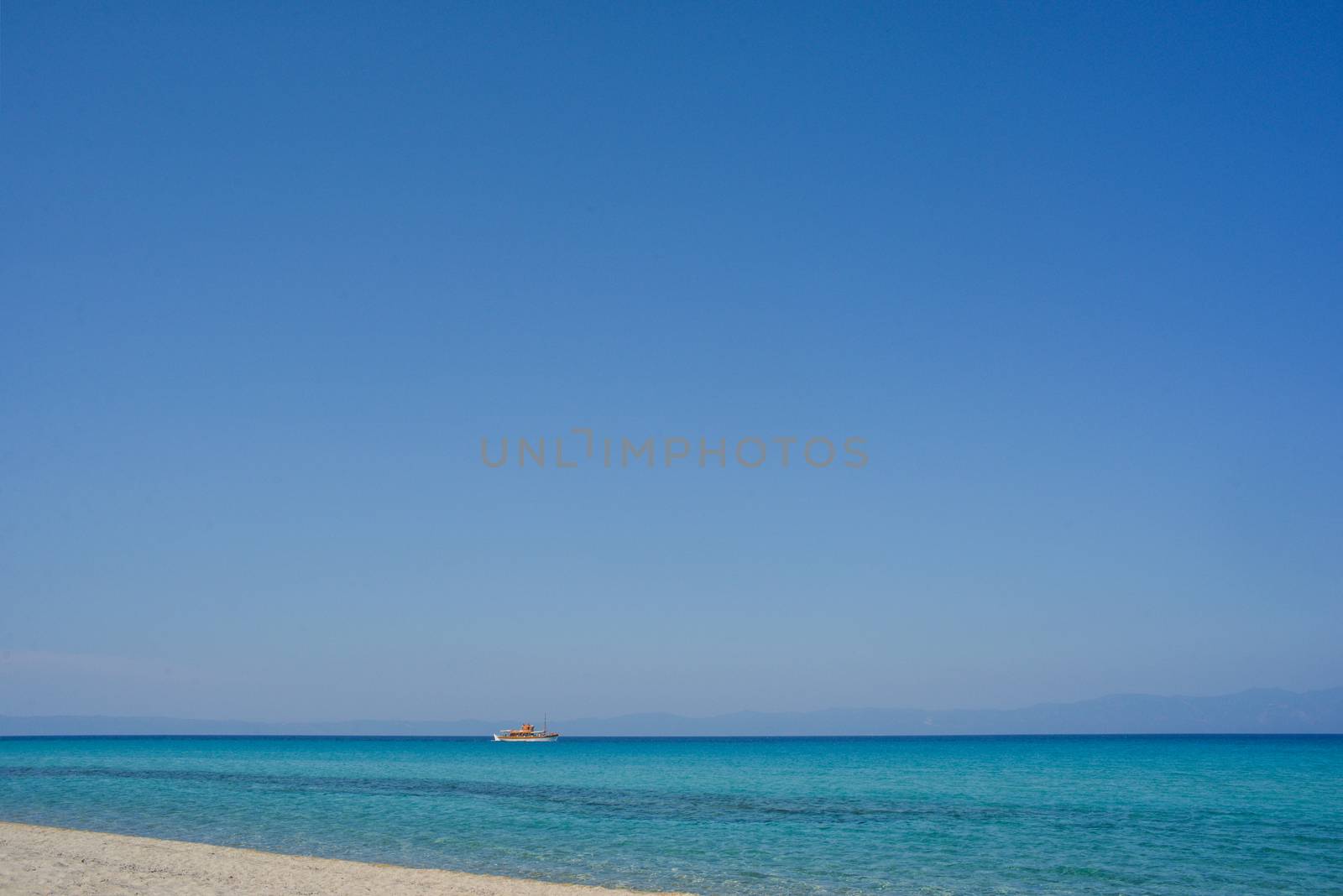 An empty beautiful seashore with clear sky and a tourist boat.