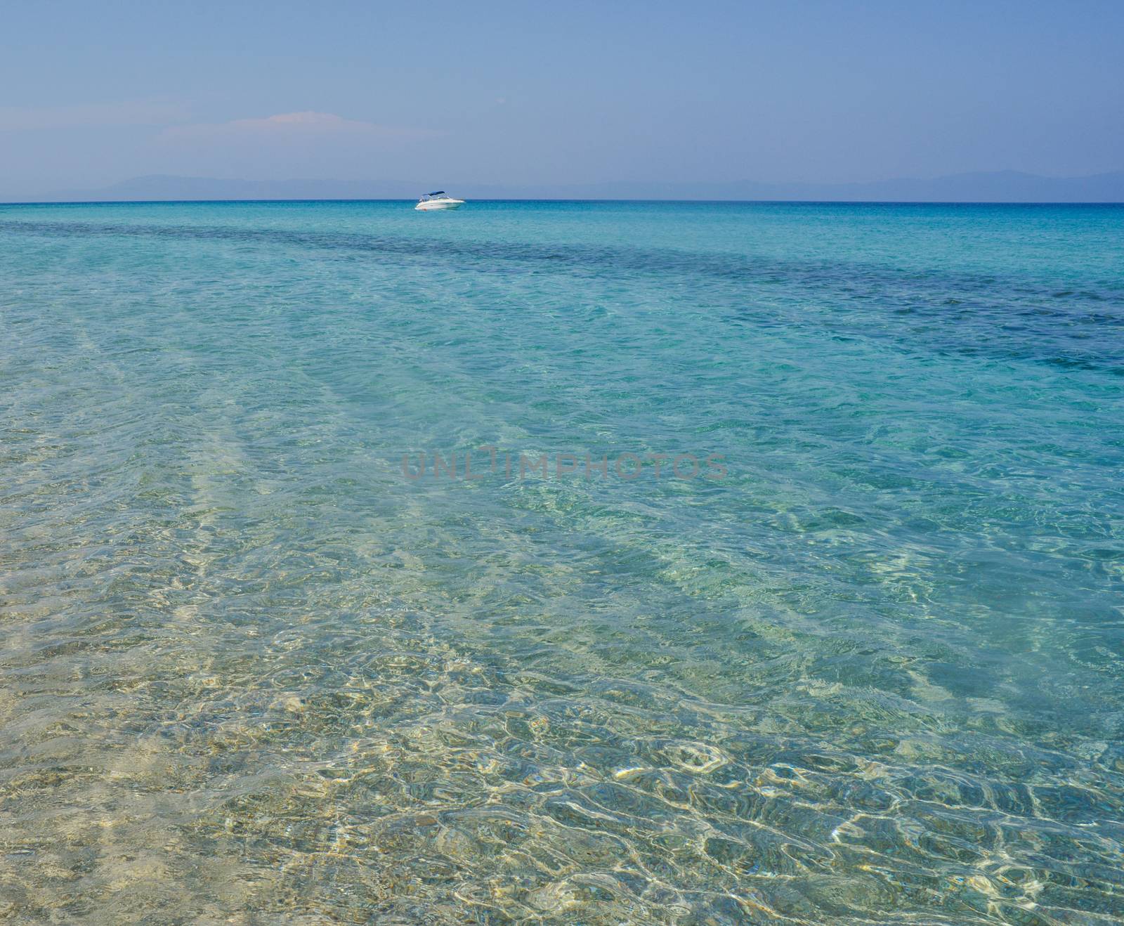 A distant yacht in clear blue waters of greek sea.