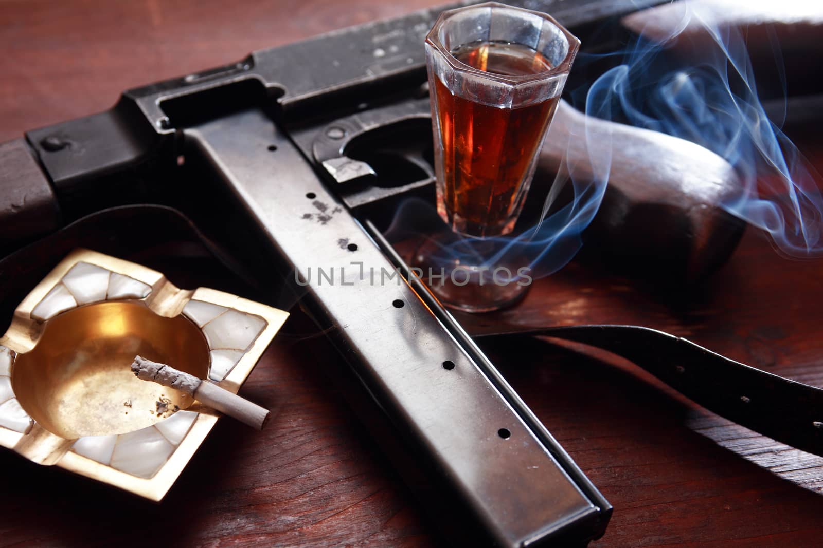 Prohabitation concept. Old USA submachine gun near drink and cigarette