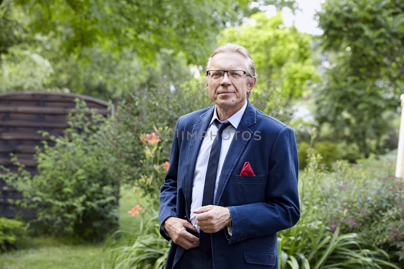 Portrait of middle-aged man wearing blue jacket in the garden. Natural sunlight.