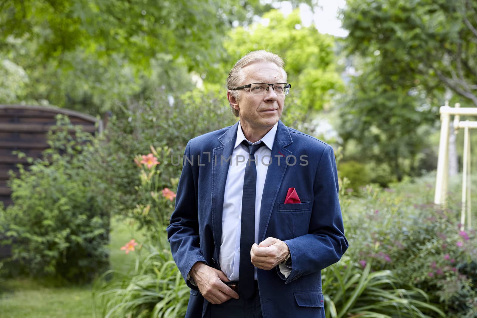 Portrait of middle-aged man wearing blue jacket in the garden. Natural sunlight.