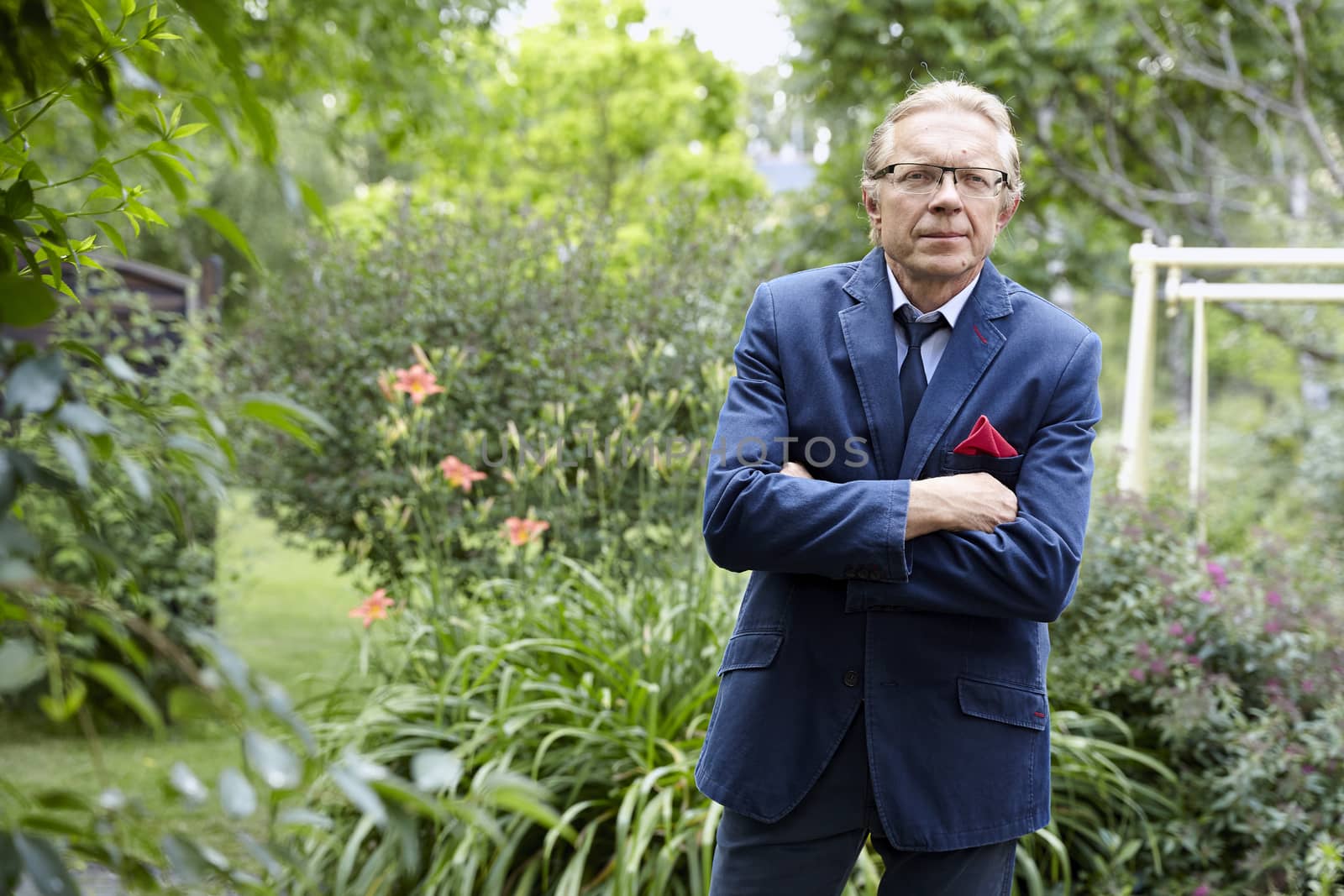 Portrait of middle-aged man wearing blue jacket in the garden. Natural sunlight.