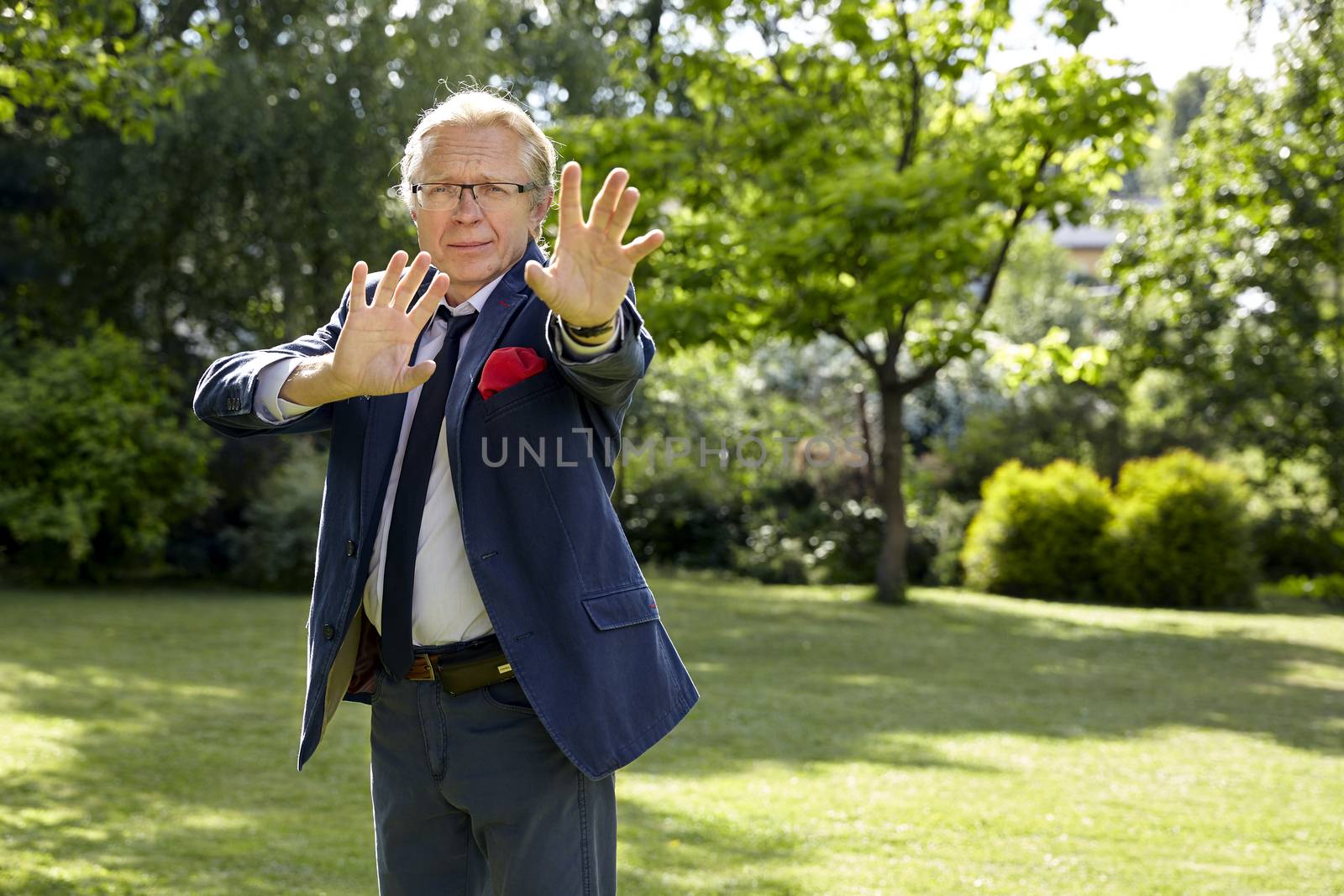 Portrait of gesticulate man in the garden at sunny day. Natural sunlight.