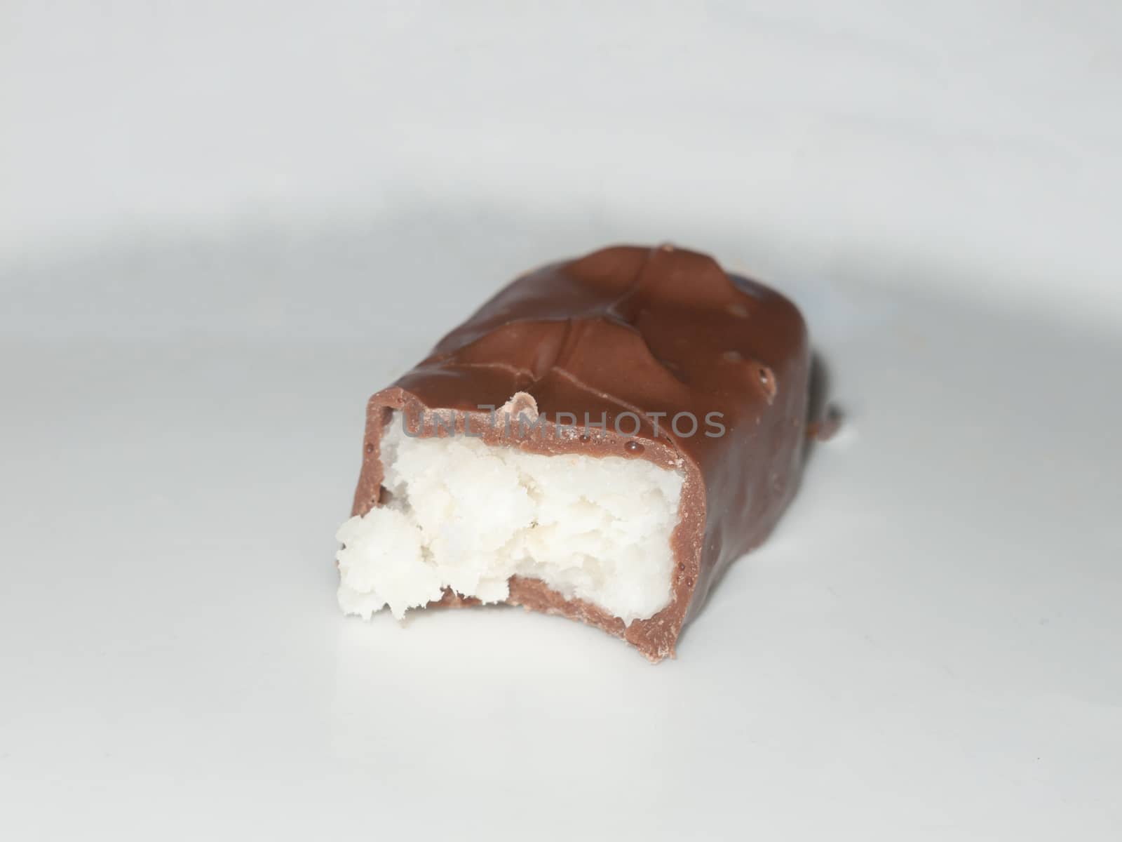 brown chocolate bounty bar on white surface sweets food half eaten; essex; england; uk