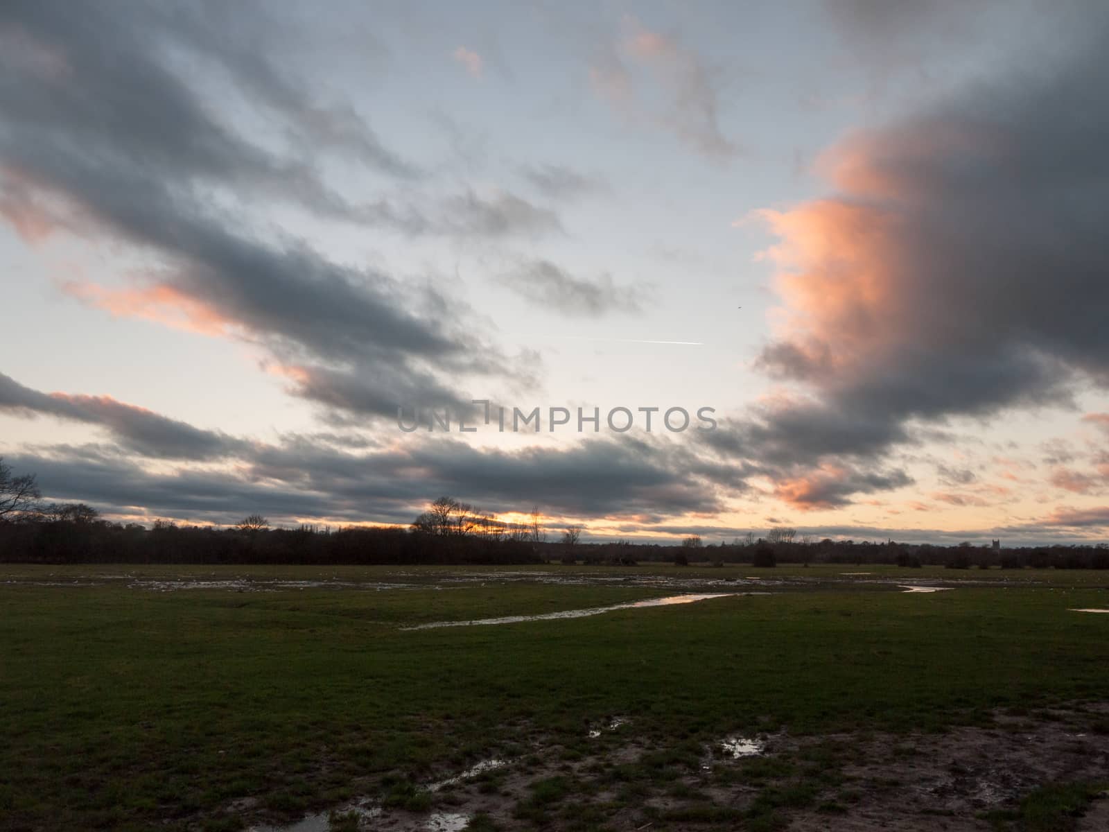 sunset moody sky winter autumn over green field with trees water by callumrc