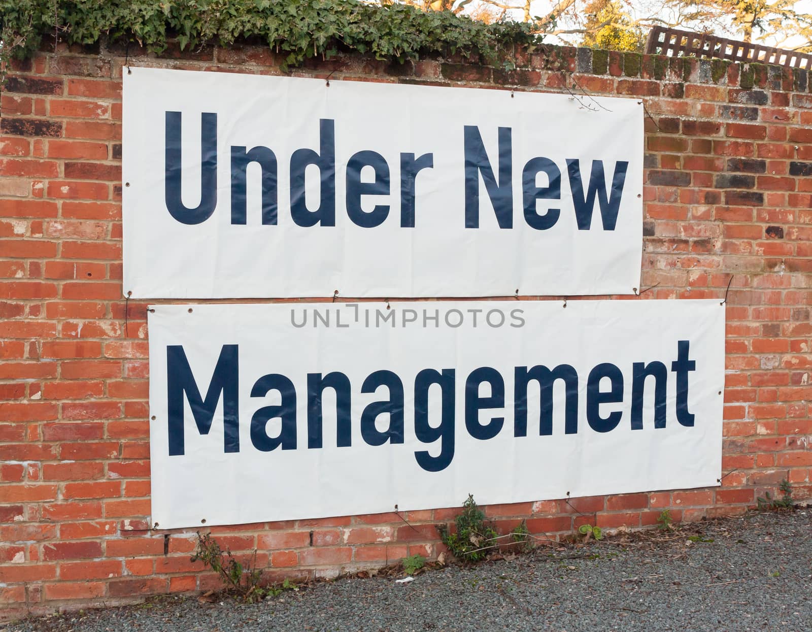 big large white and black sign on brick wall under new management; essex; england; uk