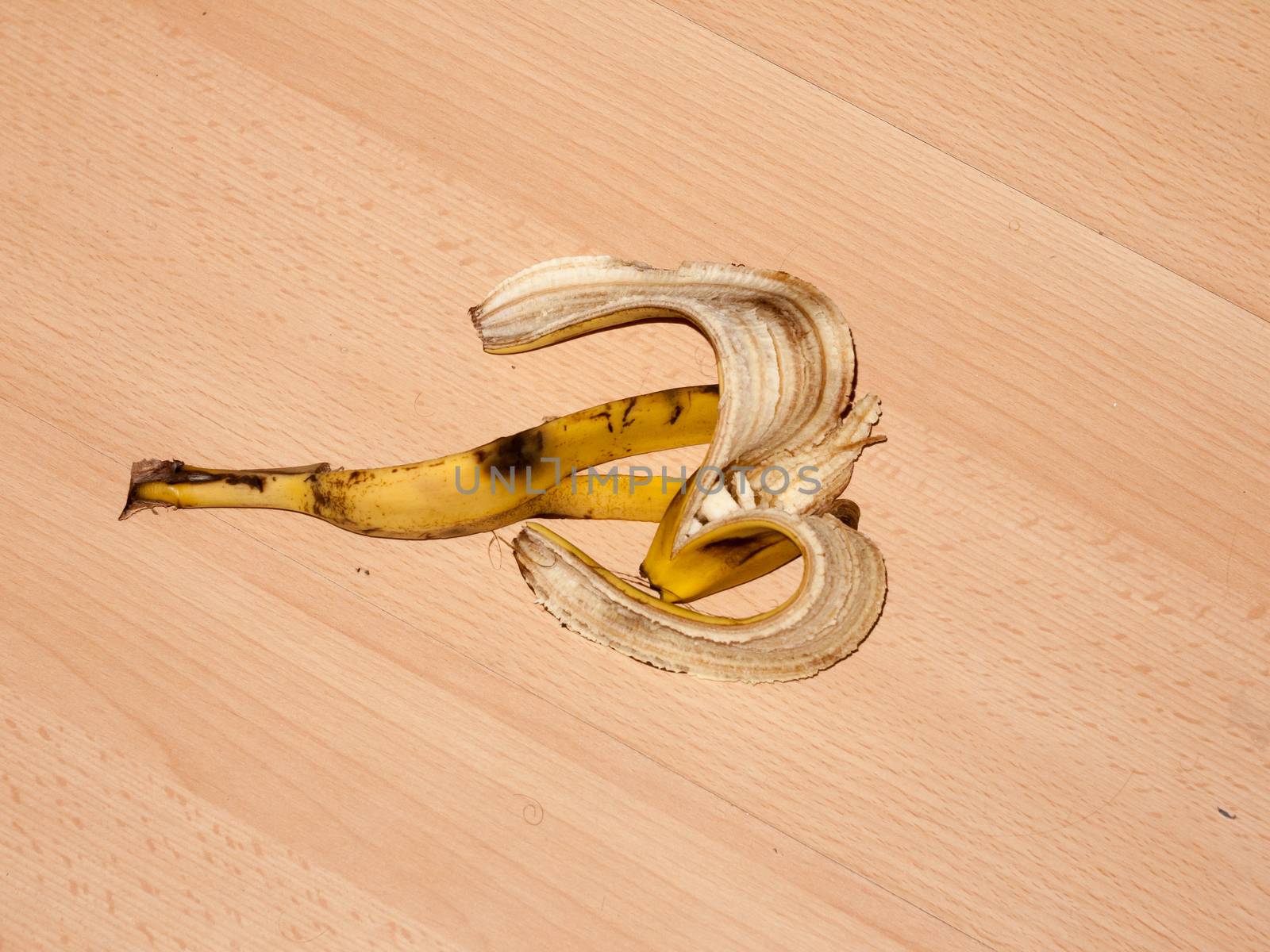 peeled banana skin on wooden laminate flooring danger hazard food; essex; england; uk