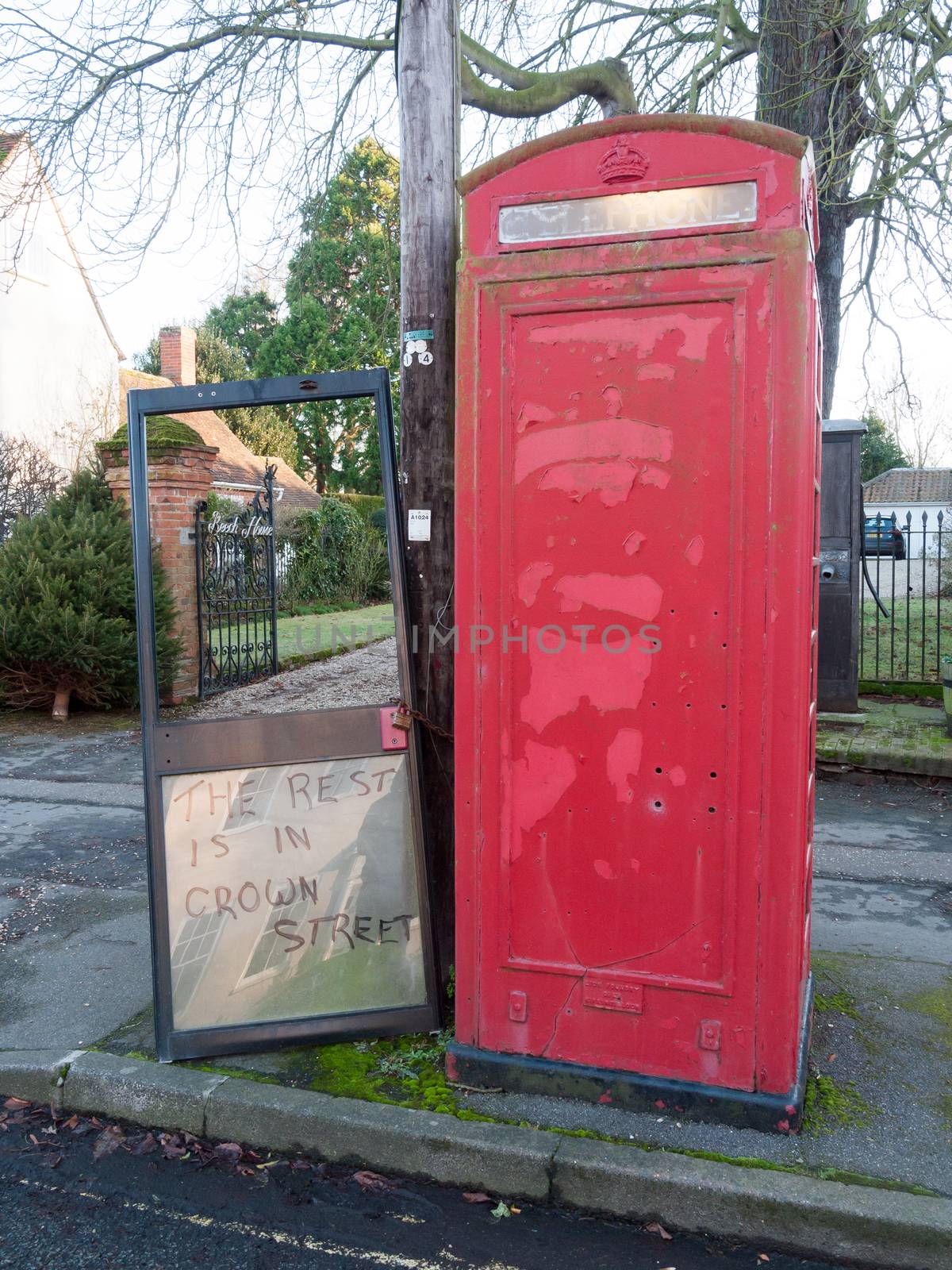 red telephone box with hanging stolen door chained to; essex; england; uk