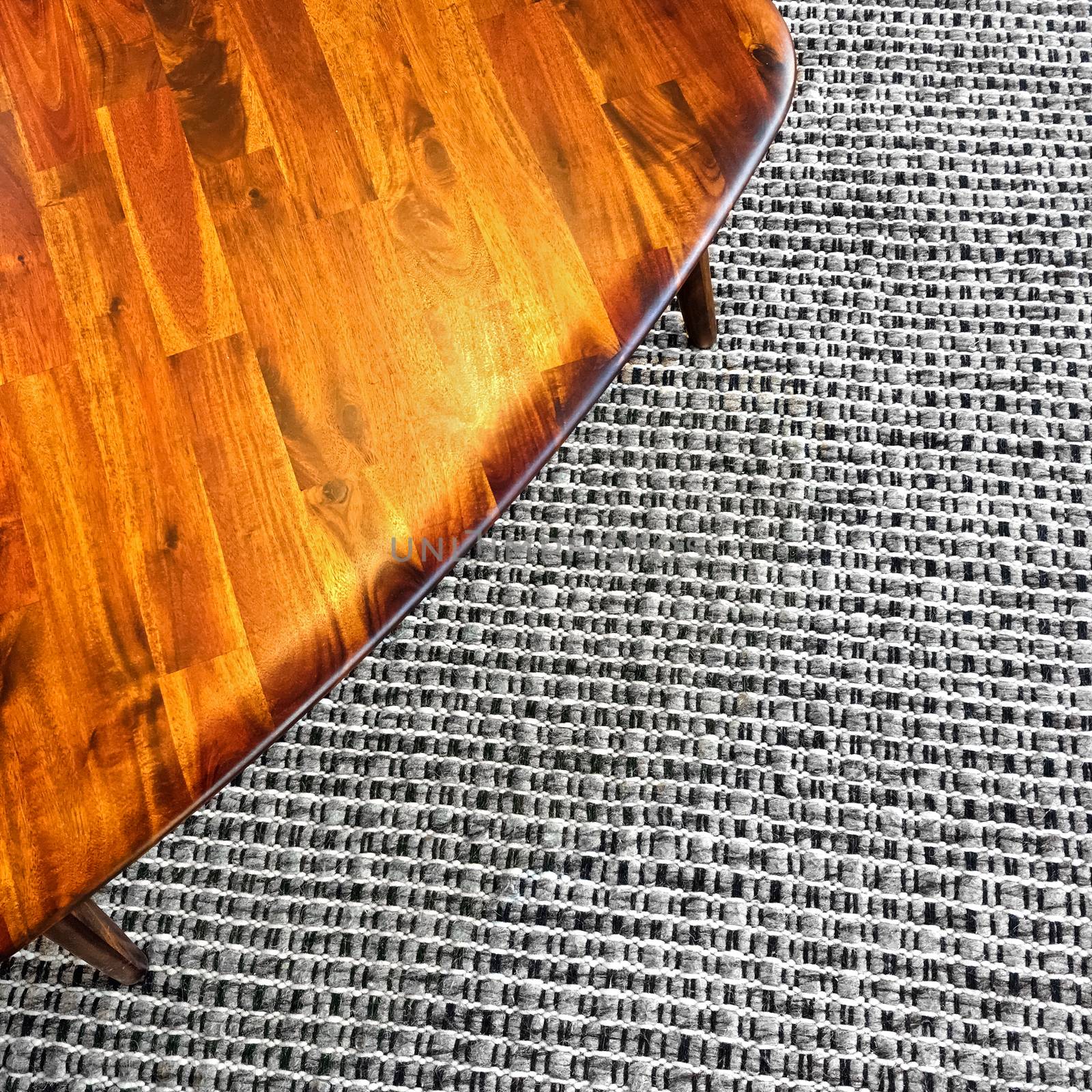 Wooden table on gray rug. Modern design with retro feel.