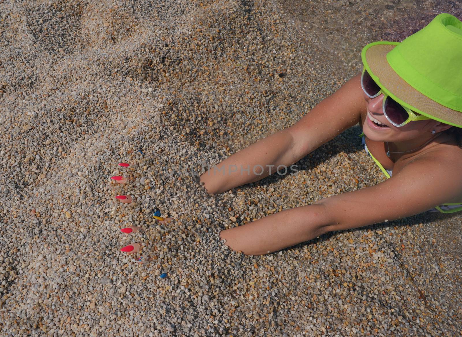 Happy female lying on the sand of a calm seashore.