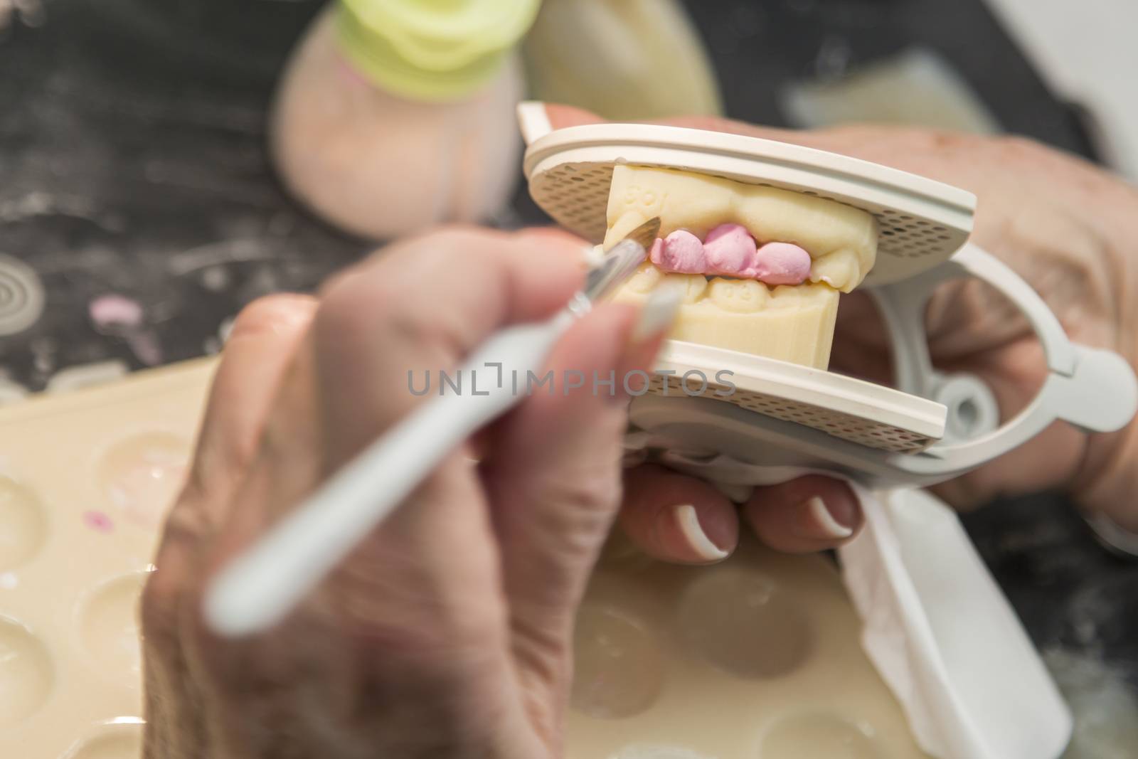 Female Dental Technician Applying Porcelain To A 3D Printed Implant Mold In The Lab. by Feverpitched