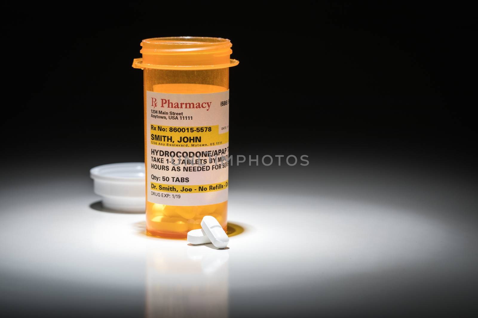 Hydrocodone Pills and Prescription Bottle with Non Proprietary Label. No model release required - contains ficticious information. by Feverpitched