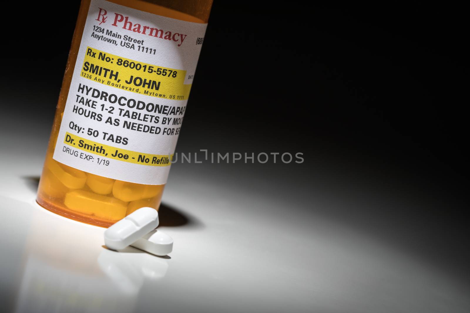 Hydrocodone Pills and Prescription Bottle with Non Proprietary Label. No model release required - contains ficticious information. by Feverpitched