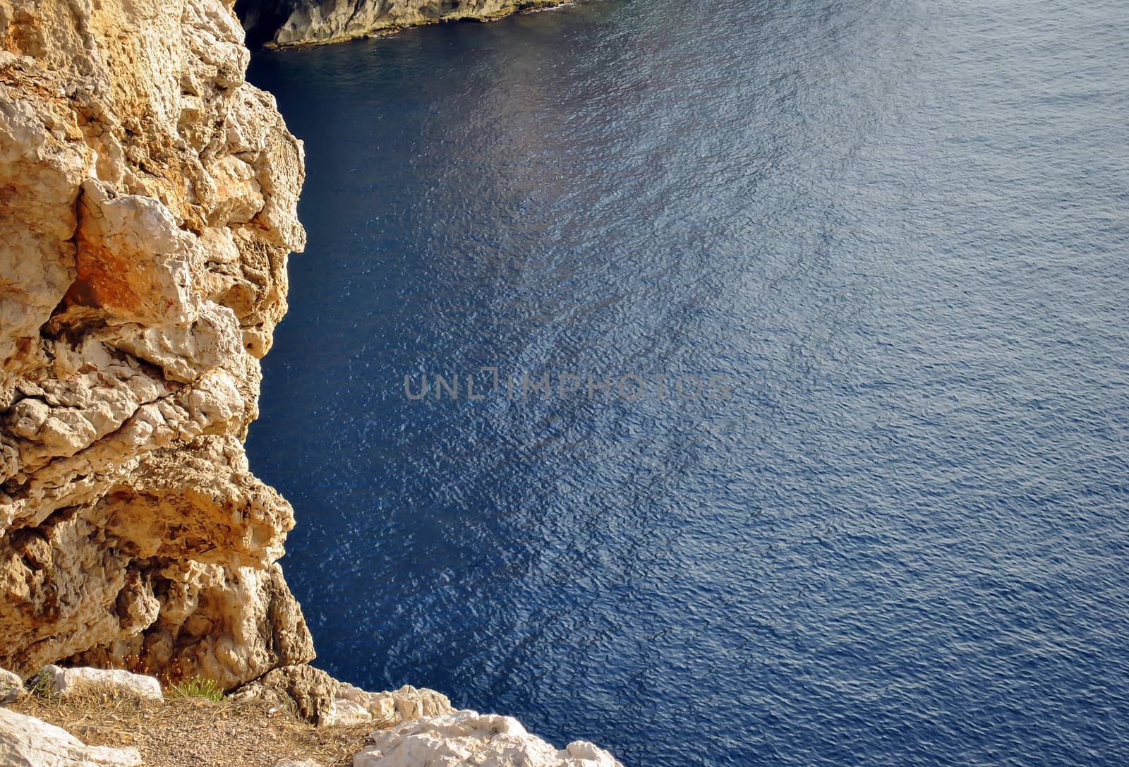 rocky coastline overlooking a blue calm sea in Sardinia, Italy
