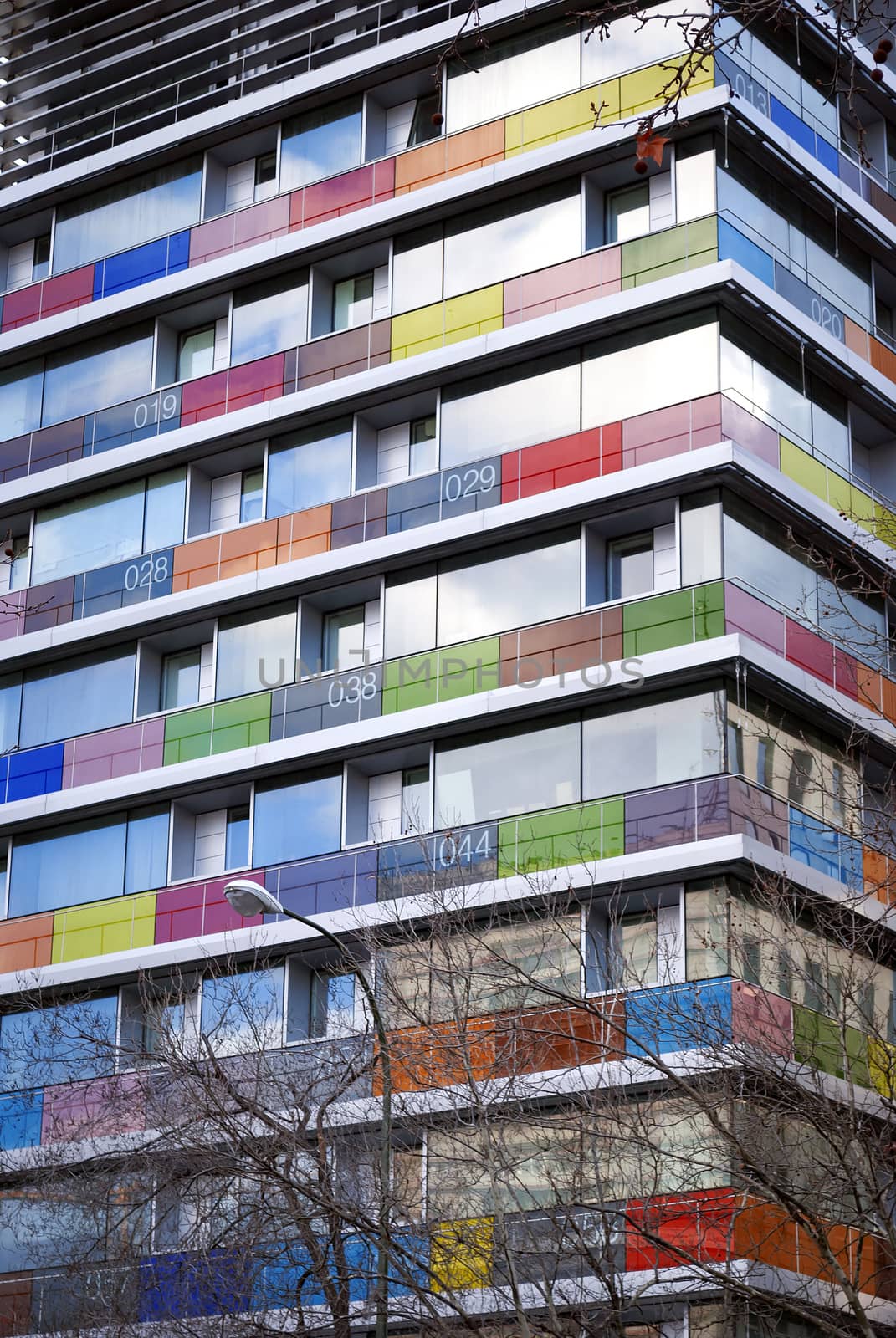 Bottom view of a modern building with colored and numbered glass balconies.