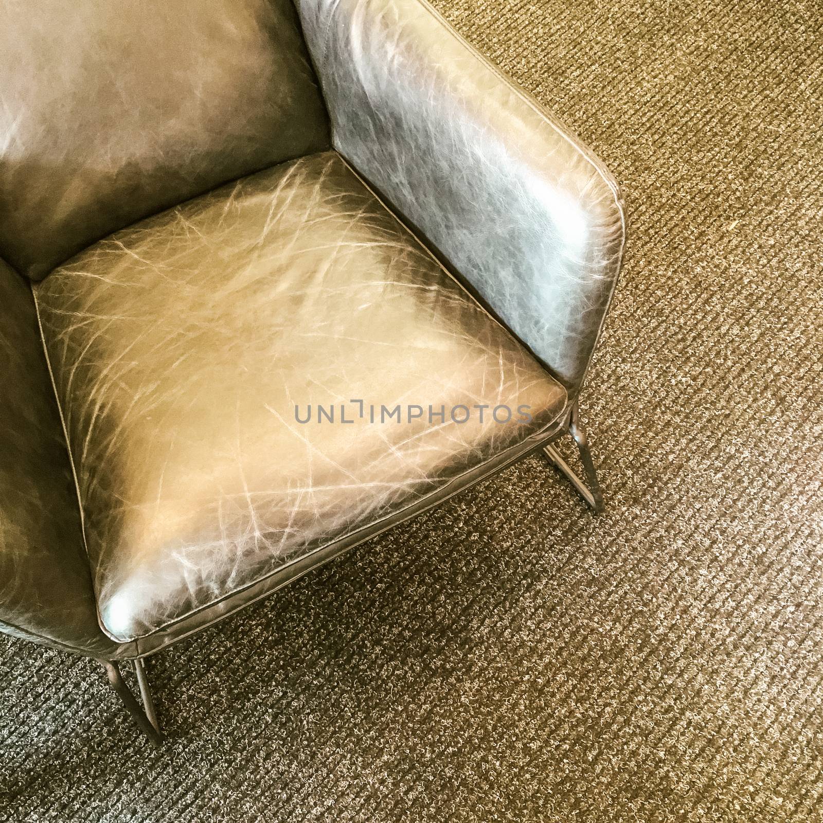 Gray leather armchair on carpet floor. Modern design with retro feel.