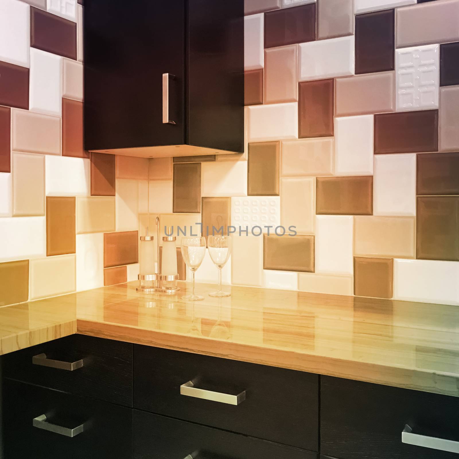 Modern kitchen cabinets and tiled backsplash in warm colors.